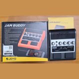 Fotografie zobrazuje černý kytarový pedálový zesilovač s nápisem JAM BUDDY a logem JOYO. Zařízení má pět ovládacích knoflíků s popisky F BACK, DELAY…