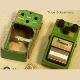 Dvě zelené kytarové efektové pedály. Pravá pedál má tři černé oválné knoflíky a štítek s nápisy Ibanez, TS9 a Tube Screamer. Levá pedál je rozebraná,…