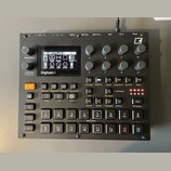 Černý sampler Digitakt II s displejem a řadou ovládacích prvků. Na přístroji jsou viditelná tlačítka, otočné knoflíky a v pravém horním rohu logo Ele…