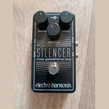 Černý kytarový pedál s nápisem THE SILENCER a podtitulem noise gate/effects loop. Na spodní části je bílé logo electro-harmonix. Zařízení má tři čern…