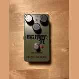 Zelený efekt pedál s třemi černými ovládacími knoflíky. Na přední straně je nápis BIG MUFF π, pod ním slovo ОВЕРДРАЙВ a značka electro-harmonix. V ho…