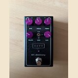 Kytarový efekt pedál v černé barvě s fialovými ovládacími knoflíky. Na horní straně jsou nápisy BASS, MIDDLE a TREBLE, ve střední části VOLUME, AGGR.…