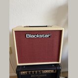 Kytarový kombozesilovač s krémovým vinylovým potahem a červenou texturovanou přední síťovkou. Uprostřed sítě je umístěno bílé logo Blackstar. Zesilov…
