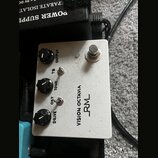 Bílý kytarový efekt s nápisy VISION OCTAVIA a logem RM. Na horní straně jsou tři černé otočné knoflíky s popisky OUTPUT, TONE a DRIVE. Mezi nimi jsou…