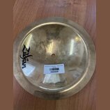 Kulatý mosazný činel s logem Zildjian. Na povrchu je nalepená bílá štítková nálepka s čárcovým kódem a textem ZILDJIAN 9-5" 24 bell large A20002 pouz…