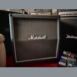 Černý kytarový kombozesilovač s bílým lemováním kolem přední mřížky. Uprostřed mřížky je umístěno bílé logo Marshall. Povrch je potahen černým textur…