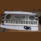 Stříbrný digitální klavír značky CASIO s plnou klaviaturou. Nástroj má dva velké a dva malé integrované reproduktory, řadu ovládacích tlačítek a disp…