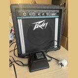 Černý přenosný kombozesilovač s logem Peavey na předním mřížkovém krytu. Horní ovládací panel obsahuje nápisy LOW Z, CHANNEL 1, MIC, CHANNEL 2, EQUAL…
