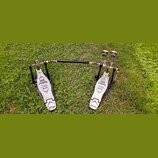 Dvojpedál na buben v černé a stříbrné barvě, umístěný na trávě. Na obou šlapkách jsou nápisy IRON COBRA, The Legend in Innovation a 600, v dolní část…