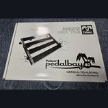 Bílá papírová krabice s černými nápisy a grafikou. Na povrchu je obrázek pedalboardu a texty „DEFINE YOUR TONE“, logo „Palmer Musical Instruments“ a…