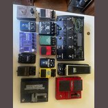 Sestava různých kytarových efektů a pedálů. Jsou zde zařízení s nápisy: „BASEBALLS“, „ DigiTech Whammy“, „Boss Metal Zone MT-2“, „BOSS TU-3“, „TC Ele…