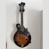 Černá mandolina s tělem v přechodové hnědo-černé barvě (sunburst) a f-otvory. Na hlavě je bílý nápis Harley Benton a dekorativní ornament. Nástroj má…