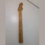 Světle hnědý javorový krk elektrické kytary s prázdnými otvory pro pražce. Na hlavě je viditelné logo Fender a nápis MADE IN USA. Krk je vybaven chro…