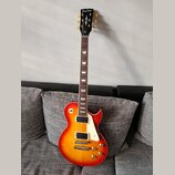 Elektrická kytara s tvarem Les Paul v červeno-žlutém sunburst provedení. Na hlavě hředu je bílý nápis Harley Benton a v dolní části logotyp s písmene…