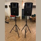 Dvě černé akustické reproboxy umístěné na černých stativech. Na přední mřížce každého reproduktoru je bílý nápis RCF. Na nohou stativů je viditelný b…