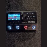 Černý kytarový procesor s displejem a ovládacími prvky. Na přístroji je bílý nápis VALETON GP-200LT MULTI-EFFECTS PROCESSOR. Displej zobrazuje text 0…