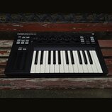 Černý MIDI kontrolér s klaviaturní klávesou. Na horním panelu je nápis KOMPLETE KONTROL S25 a v pravém horním rohu označení MK1. Zařízení obsahuje ně…