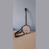 Černý banjo s bílou membránou a kovovým rímcem. Na hlavě hředu je viditelně nápis „Ruby Pearl“. K nástroji je přiložen černý popruh s bílým vzorem.