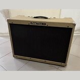 Kytarový kombo zesilovač s béžovým potahem z textilie a černou mřížkou reproduktoru. Na horní části je nápis Peavey Classic 50 v oválném rámečku. Hor…
