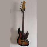 Elektrická basová kytara s tělem v provedení sunburst a hnědým hracím hřidlem. Tělo má tmavý vzorovaný pickguard a na hlavě je viditelné logo Fender.…