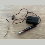 Černý kabel s červenými vodiči a stříbrným opletením, který končí v konektoru s nápisy „Belcat“ a „AP-55 AP JACK“. Součástí je černý plastový box s t…