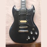 Černá elektrická kytara s dvěma humbuckery, z nichž jeden má zlatý kryt. Na těle jsou čtyři ovládací knofíky a přepínač tónu. Povrch laku vykazuje dr…