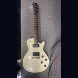 Krémová elektrická kytara s tmavým hnedým hmatníkem. Na hlavě je bílý nápis "ALBERTO". Tělo má dva humbuckery, čtyři otočné knofíky a chromovaný most…