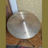 Kruhové činely typu ride z mosazného kovu s viditelnými stopami používání a drobnými škrábancemi. Na povrchu je nápis istanbul Agop Handmade cymbals…