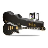 Černá elektrická kytara typu Les Paul se zlatým hardwarem a bílým lemováním. Na hlavě je logo Epiphone, na hrazence jsou vložky s nápisem „The Notori…