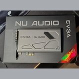 Šedá zvuková karta s kovovým krytem, položená na černém kartónovém obalu. Na krytu i na obalu je uveden nápis EVGA NU AUDIO a v pravém dolním rohu kr…