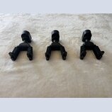 Tři černé kovové držáky na hudební nástroje. Jsou umístěny vedle sebe na světlém, texturovaném povrchu. Na předmětech nejsou viditelné žádné značky a…