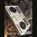 Bílý DJ controller s dvěma jogovými koly a ovládacími prvky. Na přístroji jsou viditelné nápisy Numark a MIXTRACK PLATTER. Povrch vykazuje známky pou…