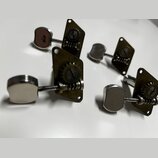 Čtyři kovové ladicí mechanismy s chromovanými knoflíky. Mechanizmy mají mosazný nebo pozlacený povrch s viditelným opotřebením a oxidací. Na dílech n…