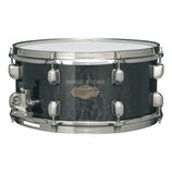 Černý snare drum s kovovým obručováním a chromovaným mechanismem. Na koruse je zlatý oválný štítek s nápisy „TAMA“, „Custom Superior“ a podpisem, kte…