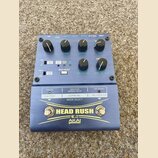 Modrý efekt pedál s nápisy HEAD RUSH a AKAI professional. Zařízení má několik ovládacích knoflíků, přepínačů a tlačítek s popisky jako MIX, HF DAMP,…