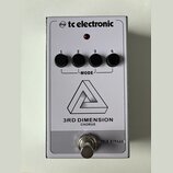 Bílý kytarový efekt s nápisem tc electronic a označením 3RD DIMENSION CHORUS. Na horní straně jsou čtyři černé otočné ovladače s čísly 1 až 4, které…
