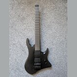 Černá elektrická kytara s matným povrchem a ostře hranatým tvarem těla. Nástroj má dva humbuckery, jeden ovládací knoflík hlasitosti a hmatník bez vi…