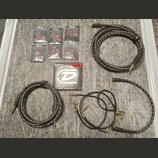 Sada příslušenství pro kytaru rozložená na šedém povrchu. Obsahuje šest balení stupenů s nápisem Ibanez GRIP WIZARD MADE IN JAPAN, krabičku strun Hea…