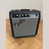 Kytarový kombo zesilovač s černým povrchem a stříbrnou textilní mřížkou. Na ovládacím panelu jsou nápisy INPUT, GAIN, VOLUME, TREBLE, BASS a POWER, p…