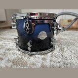 Modrý buben s kovovými obručmi a ladicími šrouby. Na korpusu je nalepený oválný štítek s nápisy „Carl Palmer“, „PLATINUM SERIES“ a „All-Maple Shell“.…