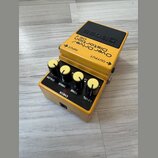 Žlutý kytarový efekt s černým horním panelem, na kterém je nápis BOSS. Na těle jsou texty OverDrive/ Distortion OS-2 a označení vstupů INPUT a OUTPUT…