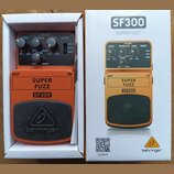 Fotografie zobrazuje oranžový kytarový efekt SF300 SUPER FUZZ značky behringer v původním bílém krabici. Pedal má čtyři ovládací knoflíky s nápisy LE…