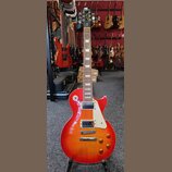 Elektrická kytara s červeným gradientním lakem a viditnou strukturou dřeva. Na hlavě je bílý nápis Epiphone a pod ním nápis Les Paul. Kytara má dva h…