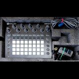 Černý sekvenční syntetizátor Novation CIRCUIT v dopravním pouzdře z pěnového materiálu. Zařízení má bílé podsvícené pady, několik otočných potenciome…