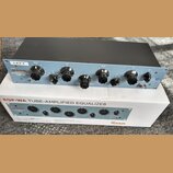 Krabice a rackové zařízení s modrým předním panelem. Na panelu je nápis WARM AUDIO PROGRAM EQUALIZER EQP-WA TUBE EQ a označení LEFT. Zařízení obsahuj…