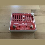 Kytarový efekt pedál v bílém šasi s červeným horním panelem. Na panelu je nápis POG2 POLYPHONIC OCTAVE GENERATOR a značka electro-harmonix MADE IN NY…