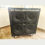 Černý basový reproduktor s kovovou mřížkou, za kterou jsou vidět čtyři velké membrány. V horní části je bílý nápis GALLIEN-KRUEGER a logo GK. Box sto…