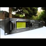 Černý rackový procesor s nápisy FRACTAL AUDIO SYSTEMS, Axe-Fx II a MARK II. Zařízení má vprostřed displej s žlutým podsvícením a textem, ovládací kno…