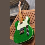 Zelená elektrická kytara typu Telecaster s třpytivým povrchem a bílým pickguardem. Má javorový hmatník a dvě snímače, z nichte jeden je humbucker. Na…