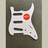 Bílá pickguard pro elektrickou kytaru s výřezy pro tři snímače. Na povrchu je nalepená červená kulatá nálepka s nápisem Fender FREE ONLINE LESSONS FO…